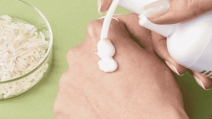 Gros plan sur une main de femme se mettant un coup de pompe de crème blanche