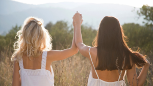 Deux femmes de dos se prenant la main en signe de victoire dans un champ