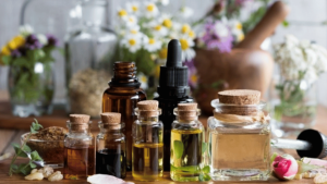 Bouteilles de différentes tailles avec bouchons de liège contenant diverses huiles essentielles sur une table décorée de différentes fleurs fraîches.