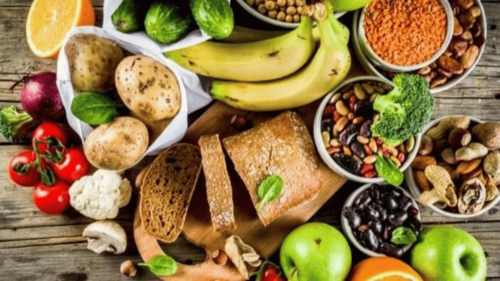 Photo d'une table remplie de fruits et légumes frais et colorés, pain entier, noix et légumineuses diverses