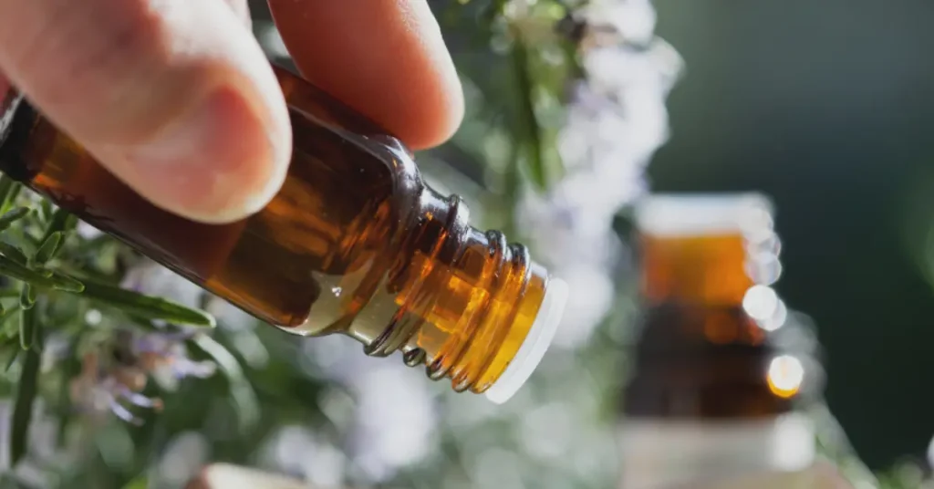 Image d'une main tenant une bouteille d'huile essentielle ambrée